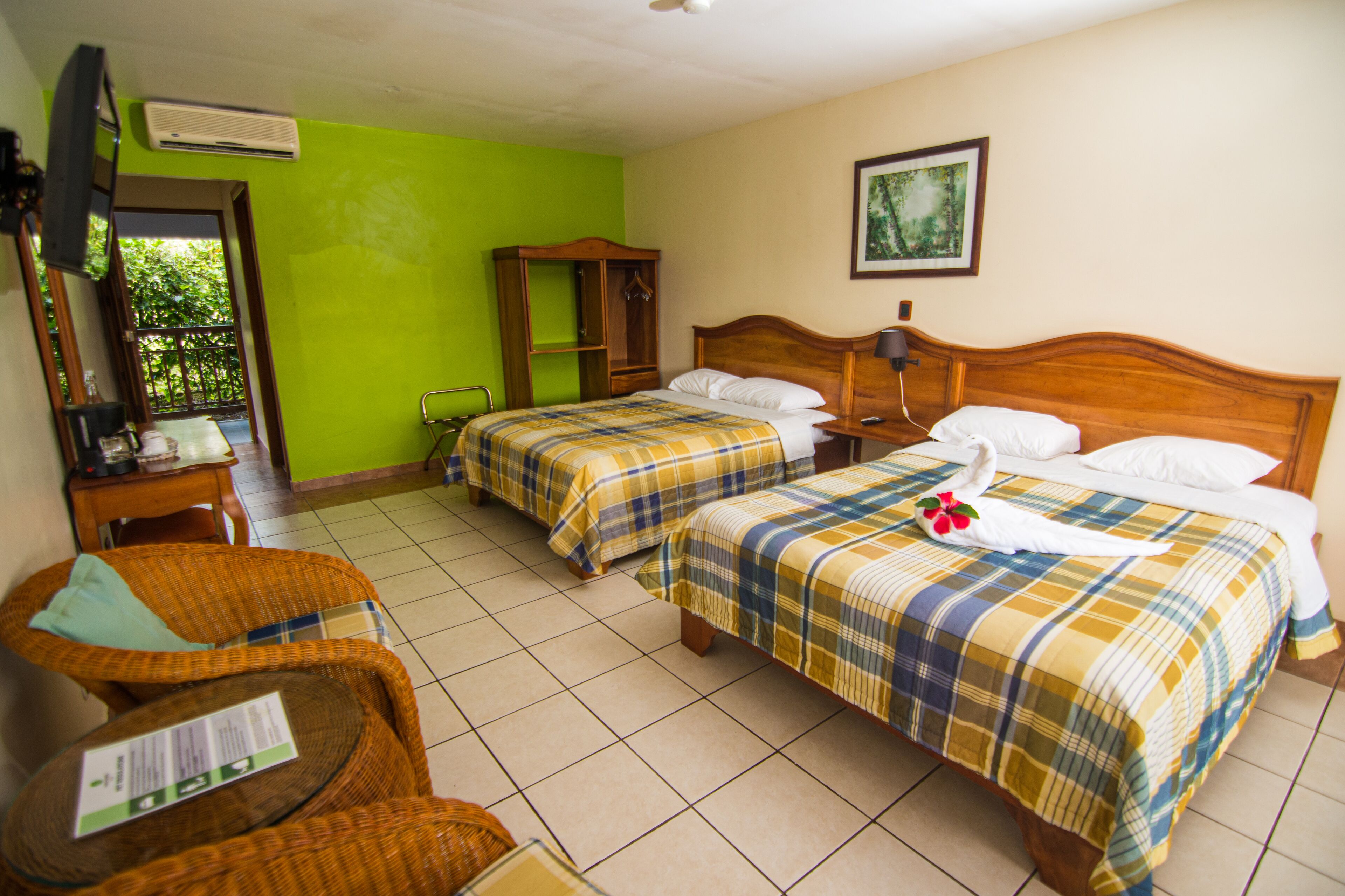 Habitación de hotel con dos camas, un armario de madera, una silla, una mesa y un televisor.