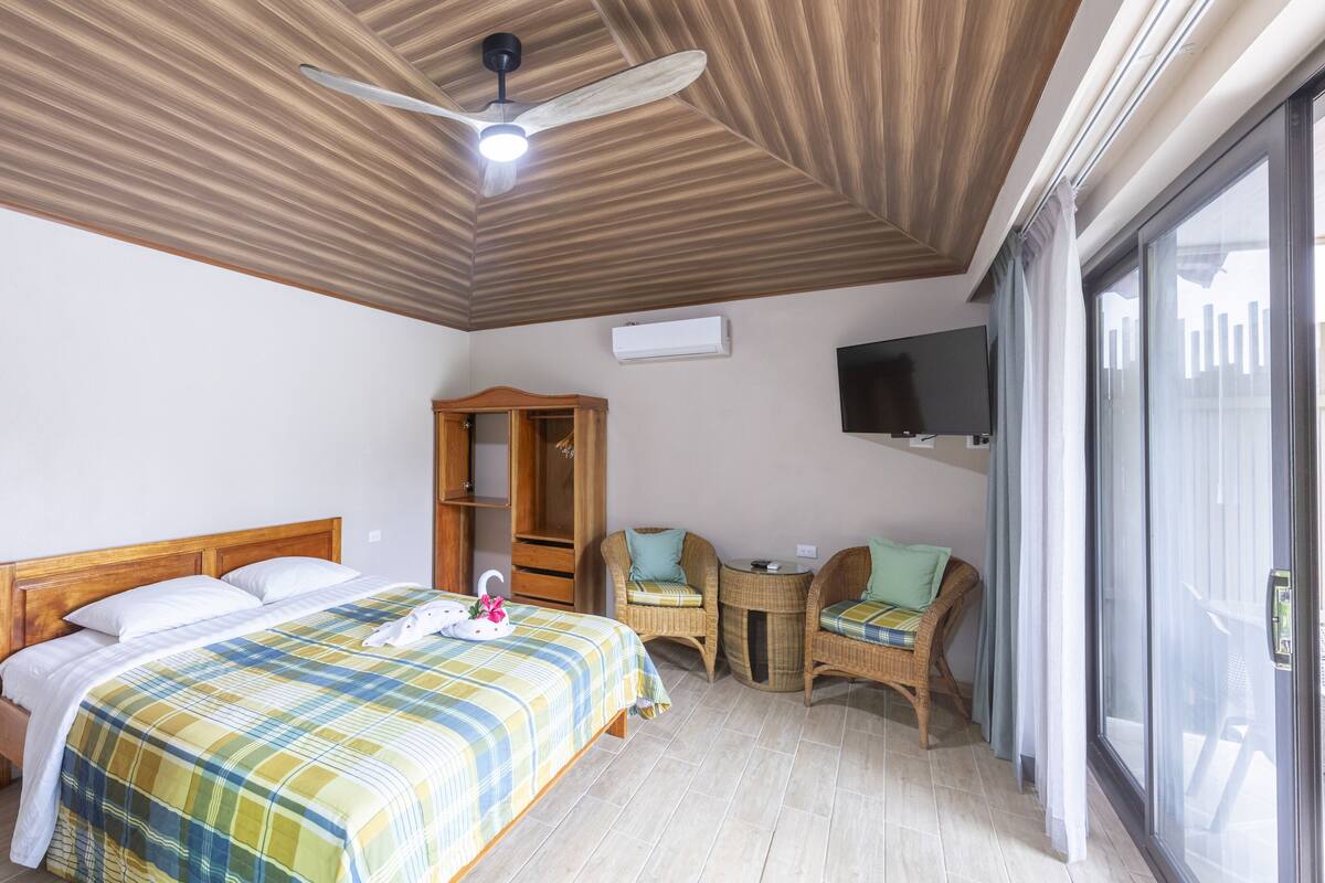 Een hotelkamer met een bed, een houten kledingkast, een televisie en een balkon.