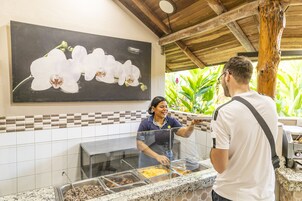 Uma área de buffet com painel de azulejos e uma grande pintura de orquídea.