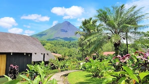 Un complexe hôtelier tropical offrant une vue sur les montagnes, une végétation luxuriante et un sentier menant aux bâtiments.
