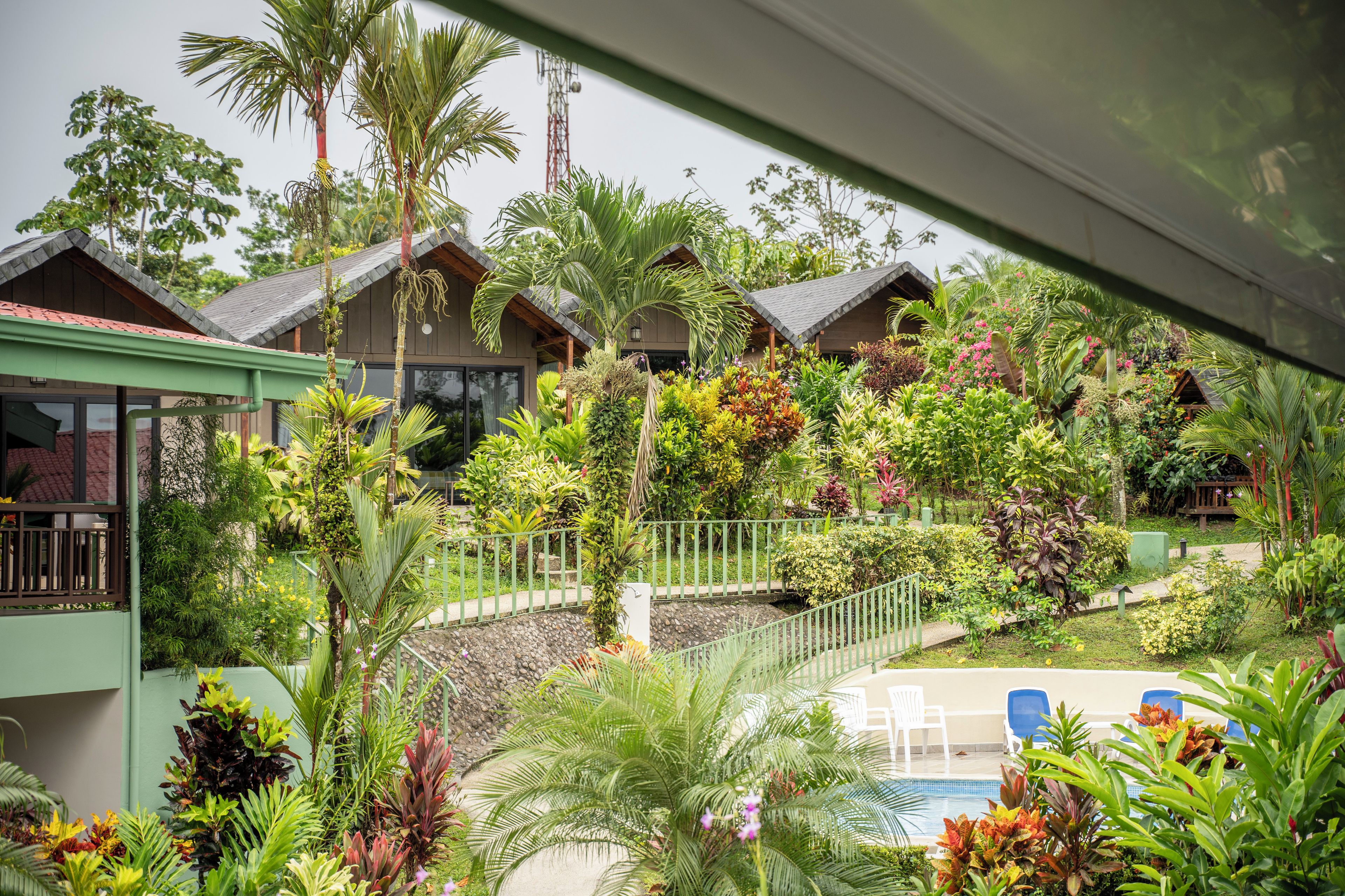 A resort with multiple bungalow-style buildings surrounded by lush tropical gardens and a swimming pool area.