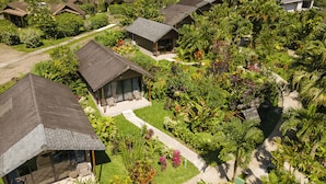 Vue aérienne d’un complexe hôtelier composé de plusieurs bâtiments de style bungalow, entourés de jardins luxuriants et de palmiers.