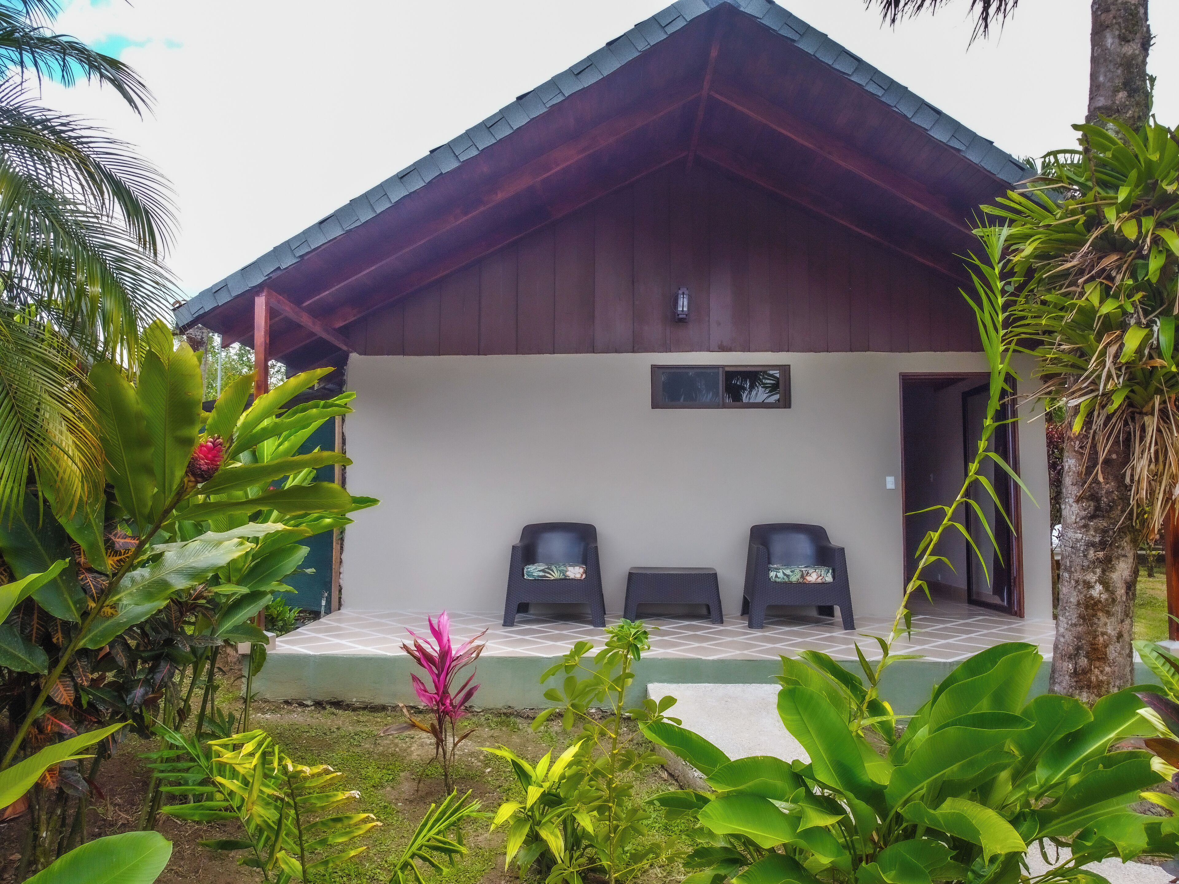 A small building with a tiled porch and two chairs.