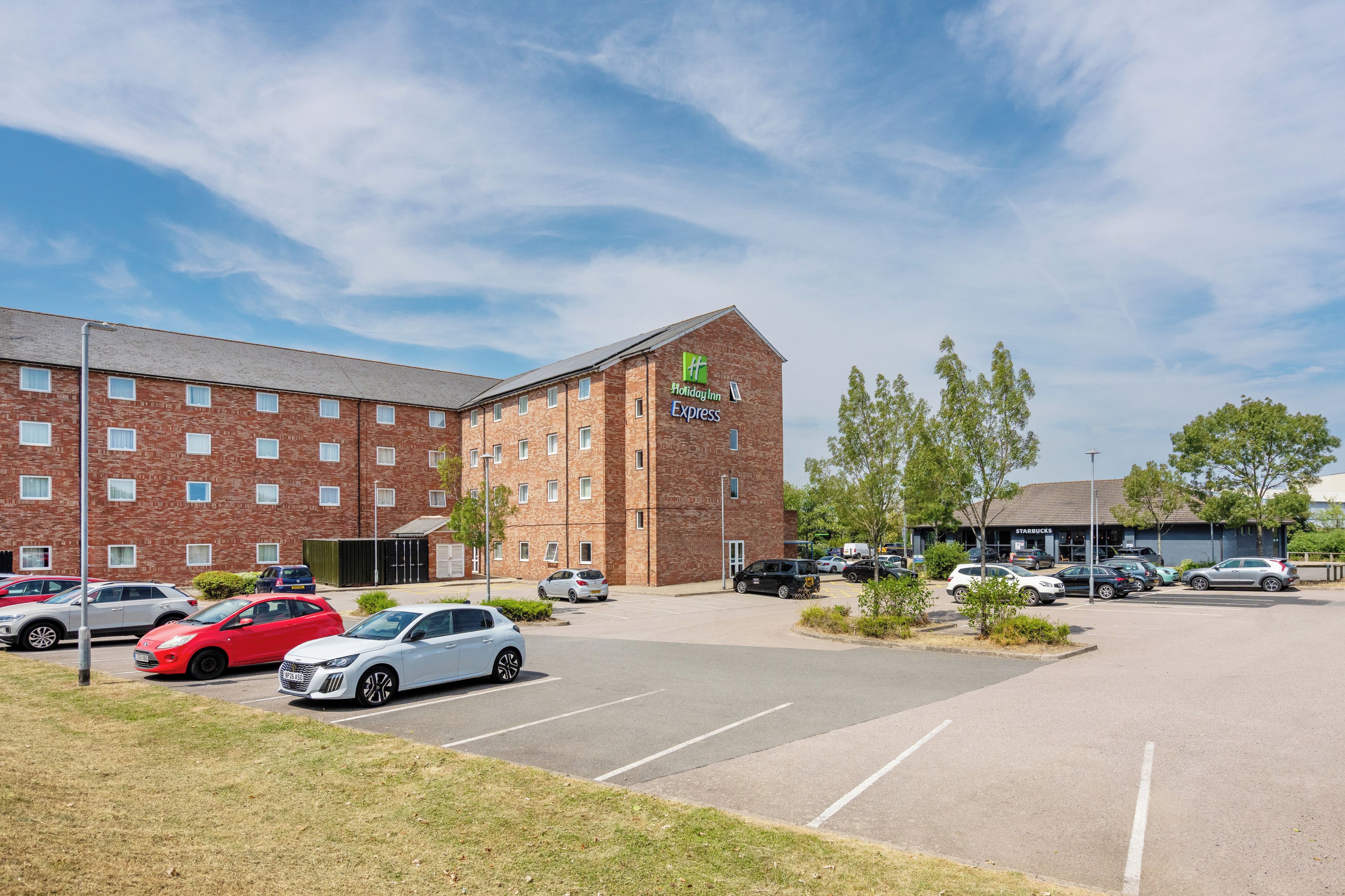 Et Holiday Inn Express hotel med parkeringsplads og flere biler.