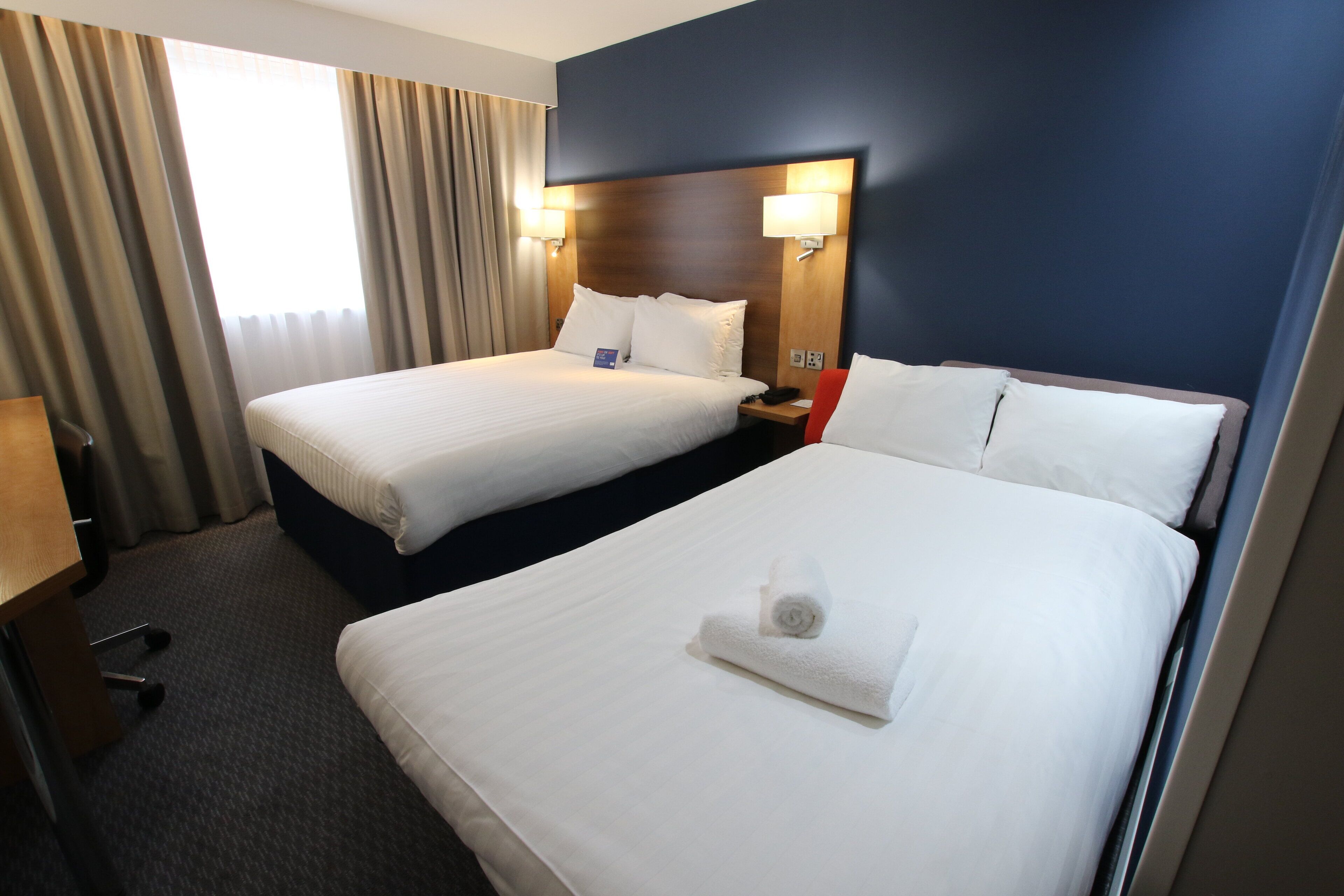 Een hotelkamer met twee bedden, een bureau en een stoel.