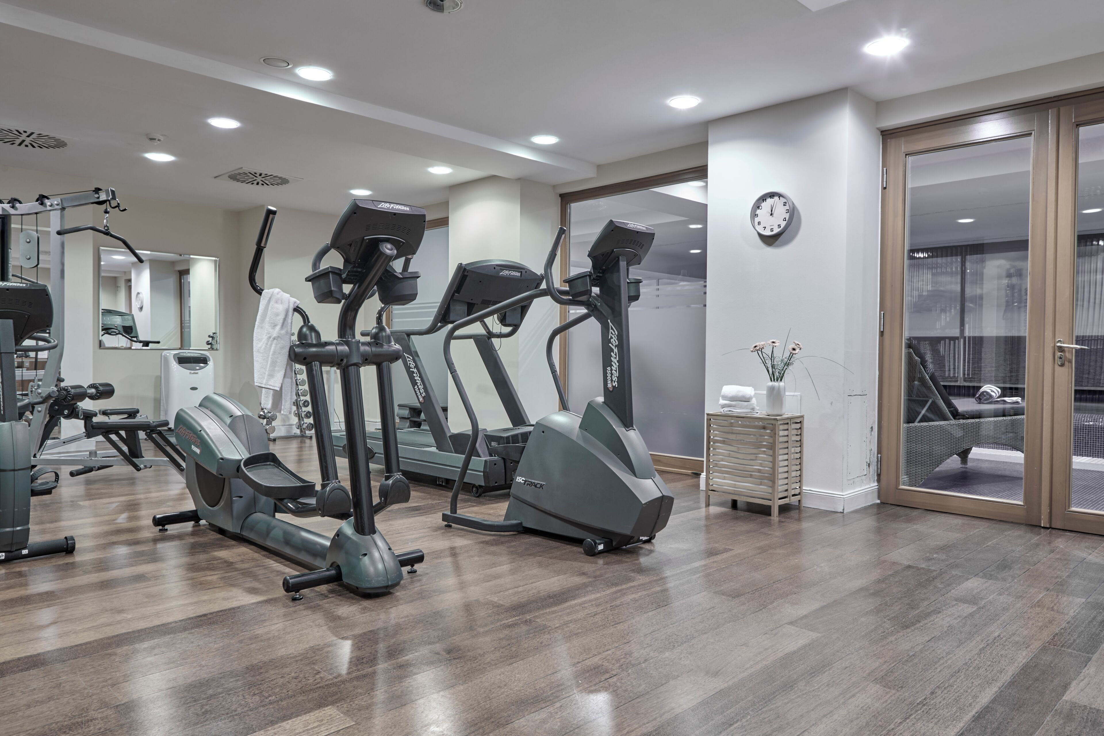 A gym with treadmills, a mirrored wall, and a clock.