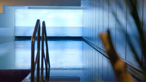 A swimming pool with a view of the sea, a chair, and a plant. - ATLANTIC Grand Hotel Travemünde (Lübeck)