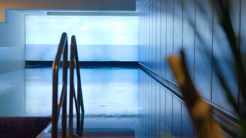 Una piscina techada, sillones reclinables de piscina