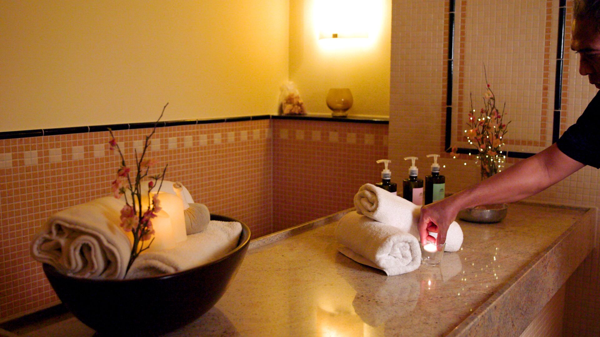 Ein Badezimmer mit Marmorplatte, einer Schale gefalteter Handtücher und Toilettenartikeln.