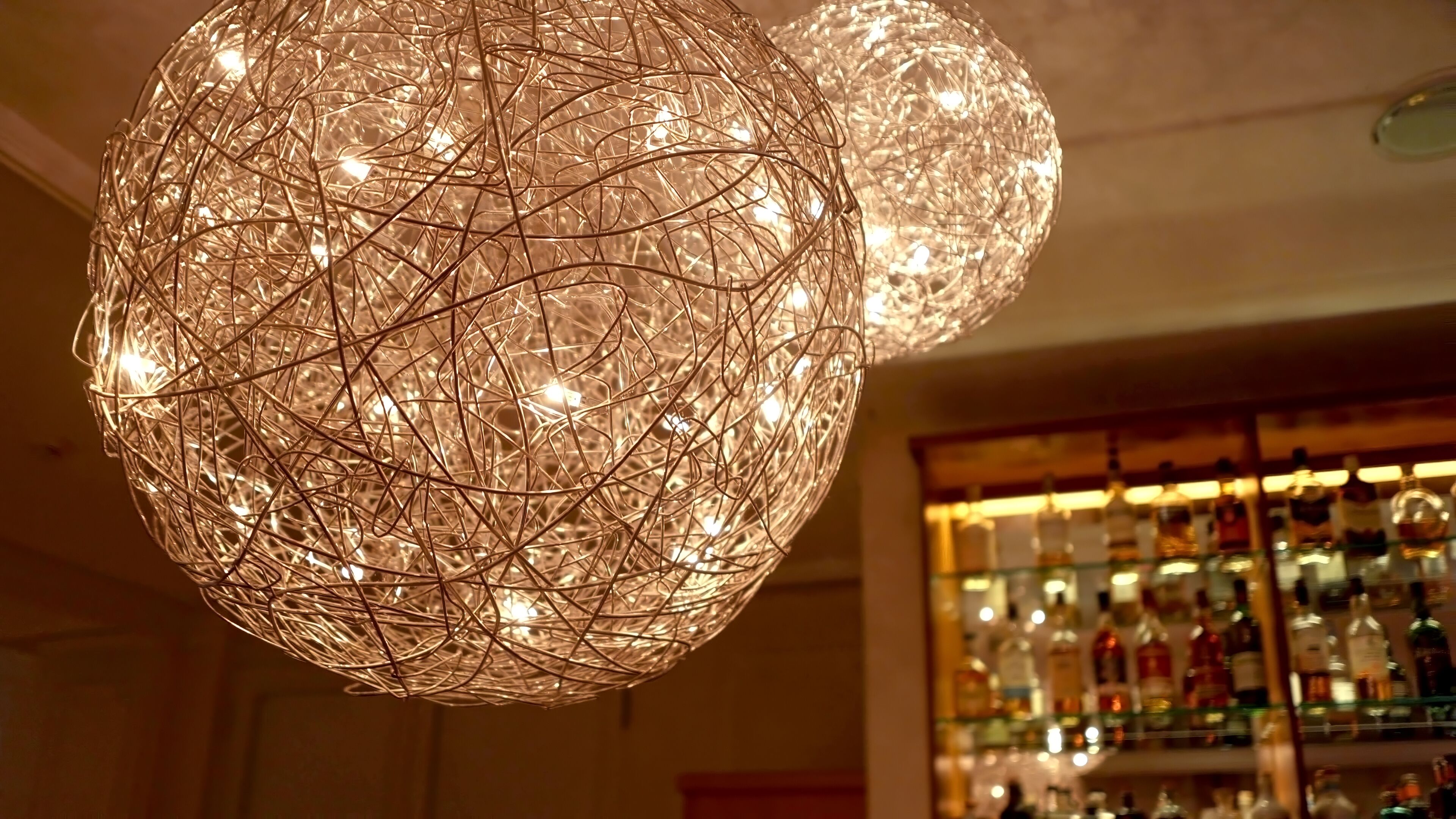 A spherical chandelier with multiple bulbs in a bar setting.