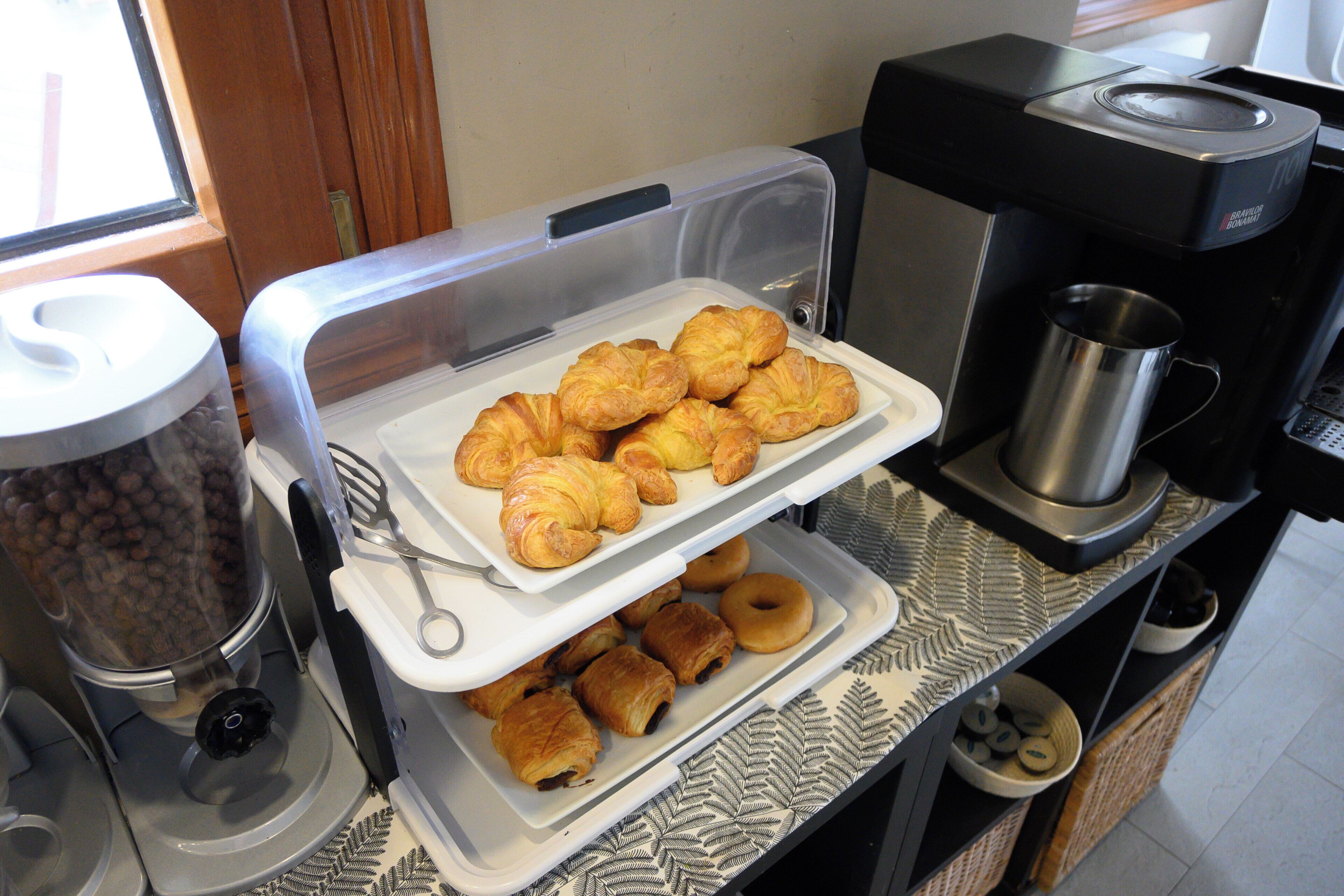 Un buffet della colazione con croissant e dolci, una macchina per caffè e una caffettiera.