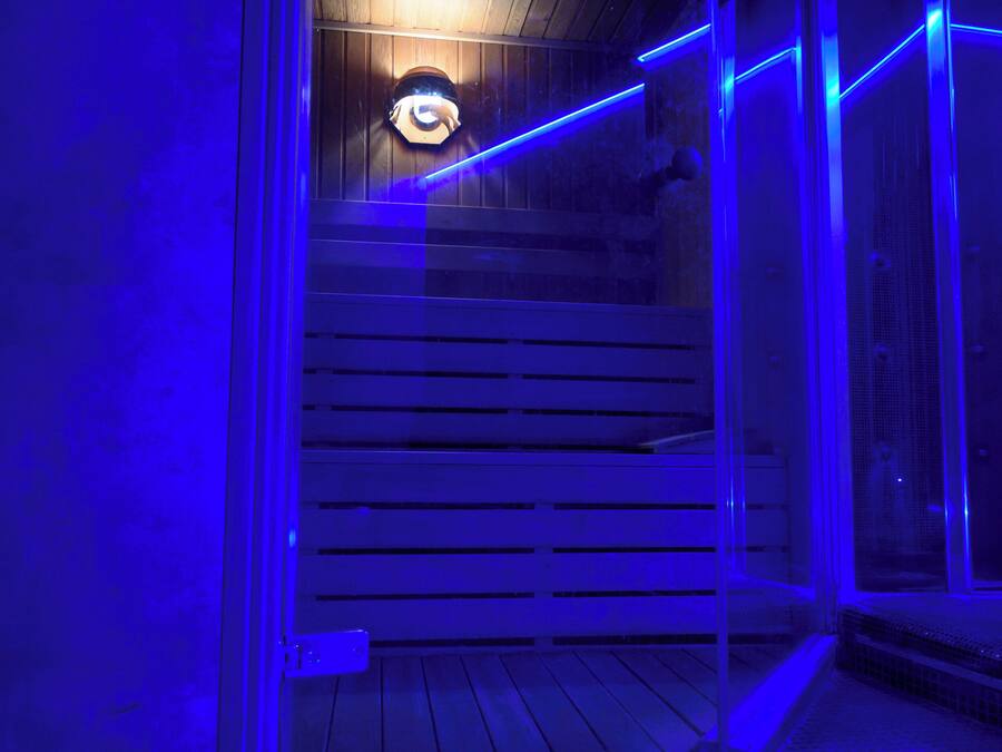 Une pièce avec un plancher en bois, un banc et un luminaire fixé au mur.