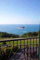 Un balcón con vista al océano y una isla distante.