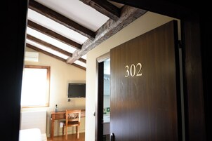 Una habitación con una puerta de madera numerada 302, un escritorio de madera y una silla.