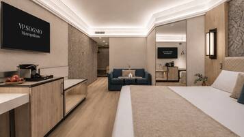 Una habitación de hotel moderna con una cama, un escritorio, un sofá y un televisor montado en la pared.