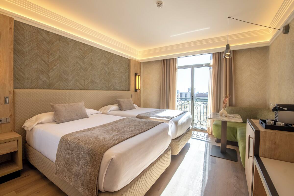 Une chambre d’hôtel avec deux lits, un bureau et une vue sur la ville.