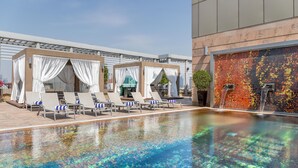 Un espace piscine aménagé sur le toit, avec des chaises longues et un mur décoré de mosaïques.