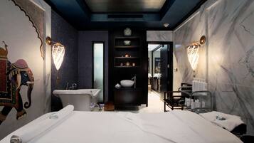 Experience a sophisticated atmosphere in this elegantly designed room featuring a large bed, classic bathtub, and unique elephant mural.