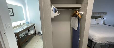 A hotel room with a bathroom, a bed, and a small seating area.