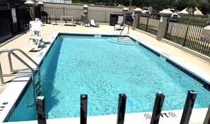 A rectangular pool with clear blue water, surrounded by a fence and equipped with a ladder.
