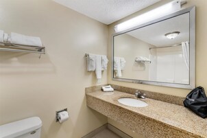 Un baño con lavamanos, espejo, toallero y retrete.