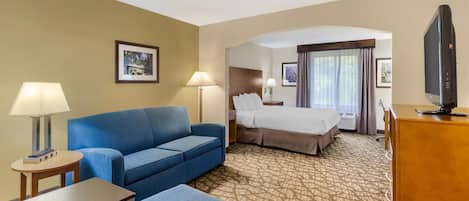 Ein Hotelzimmer mit einem blauen Sofa, einem Bett, einem Fernseher und einem kleinen Tisch.