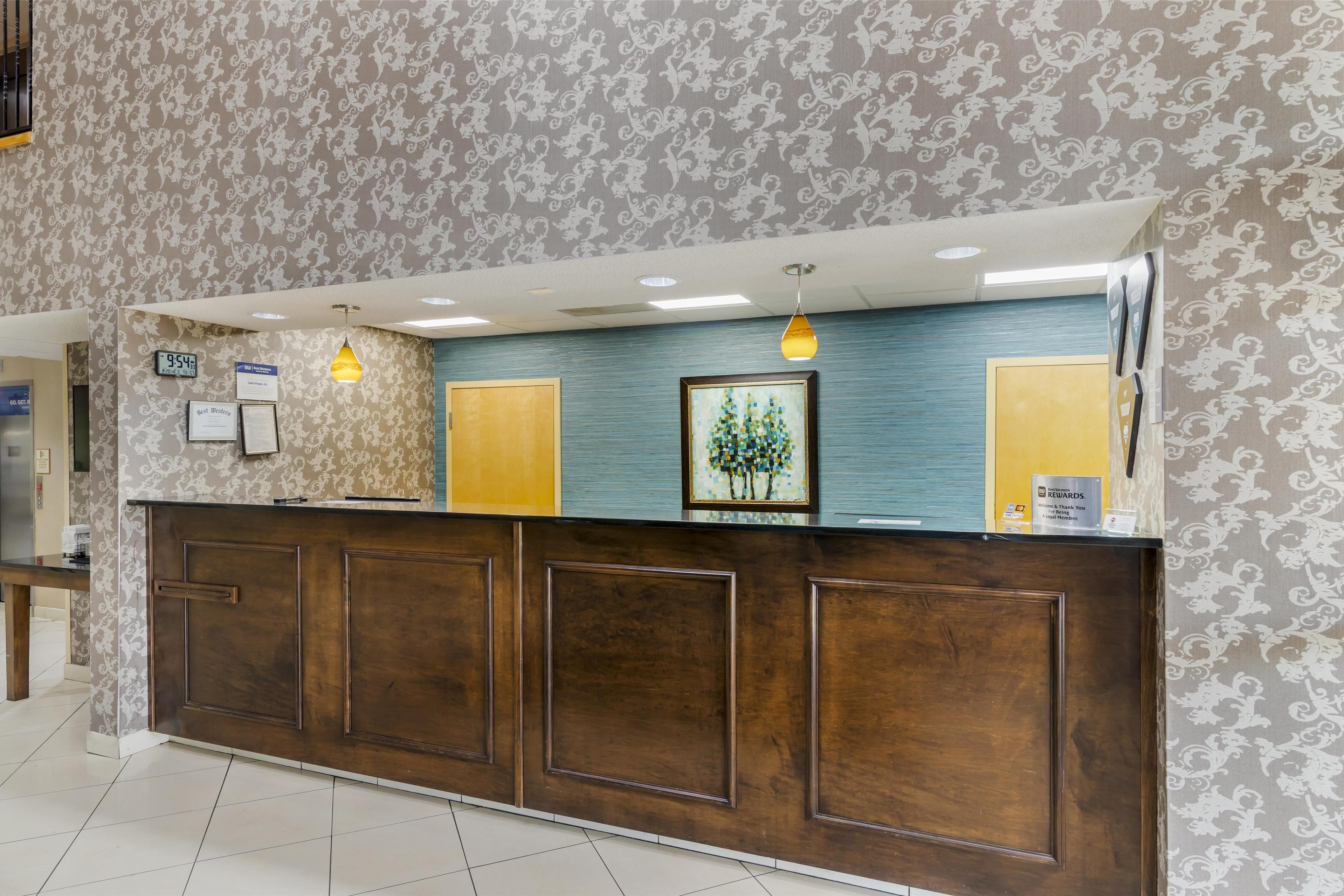 A reception desk with a clock, framed artwork, and a sign for a rewards program.