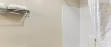 A bathroom with a toilet, a shower with a curtain, and a towel rack with two towels.