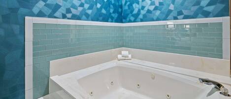 A bathroom with a freestanding bathtub, a tiled wall, and a white sink.