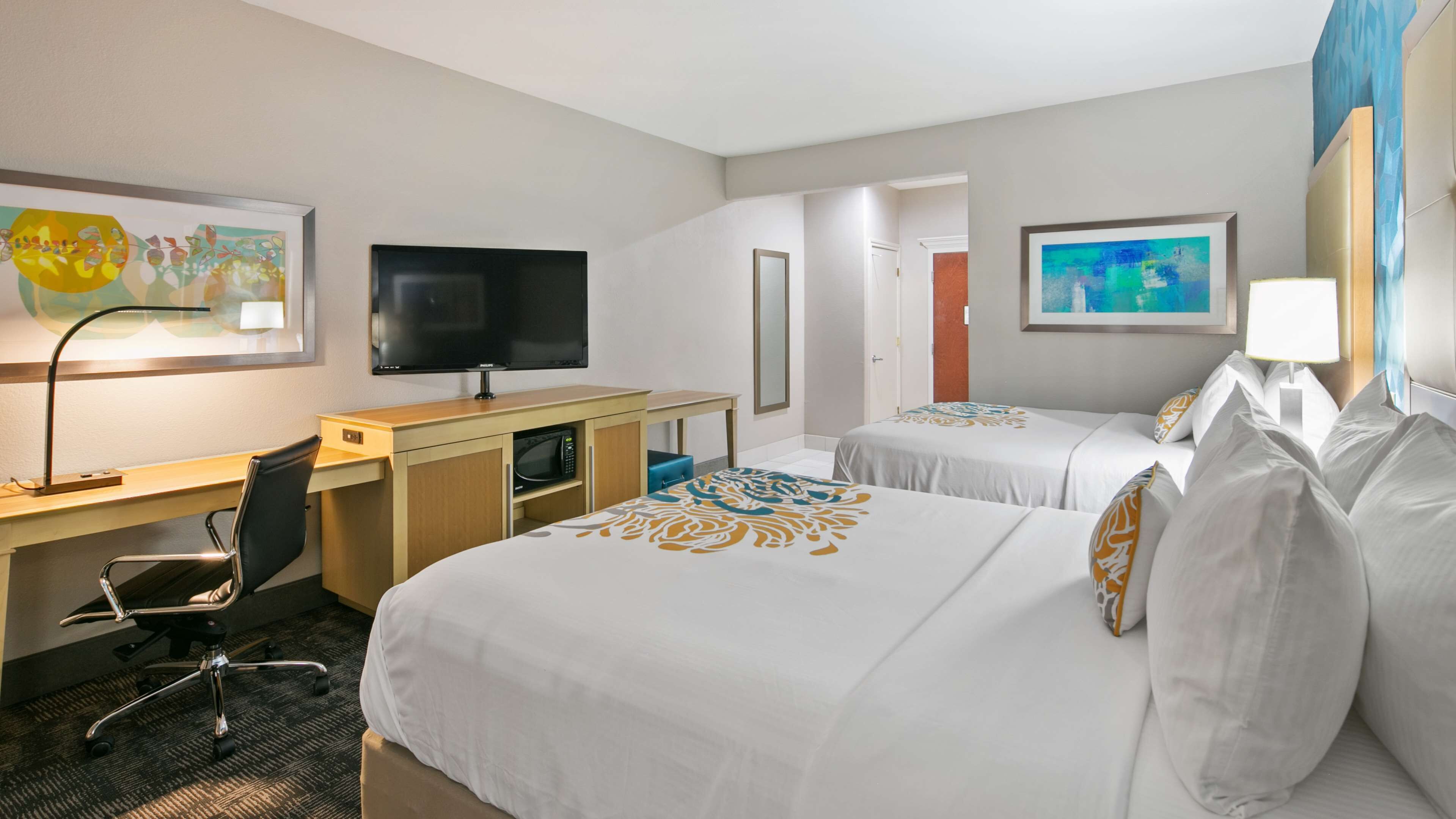 A hotel room with a bed, a desk with a computer, a television, and a microwave.