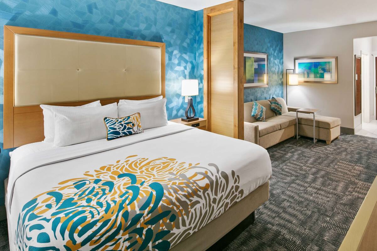A hotel room with a large bed, a desk, a television, and a sofa.
