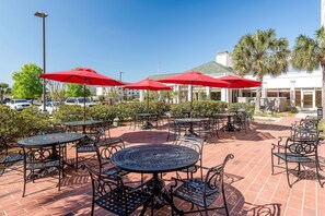 Relax in the serene outdoor patio surrounded by lush greenery and shaded seating areas.