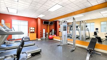 Ein Fitnessstudio mit Laufbändern, einer Hantelbank und Trainingsbällen.