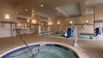 A pool area with two hot tubs, a lounge area with chairs, and a lifeguard station.