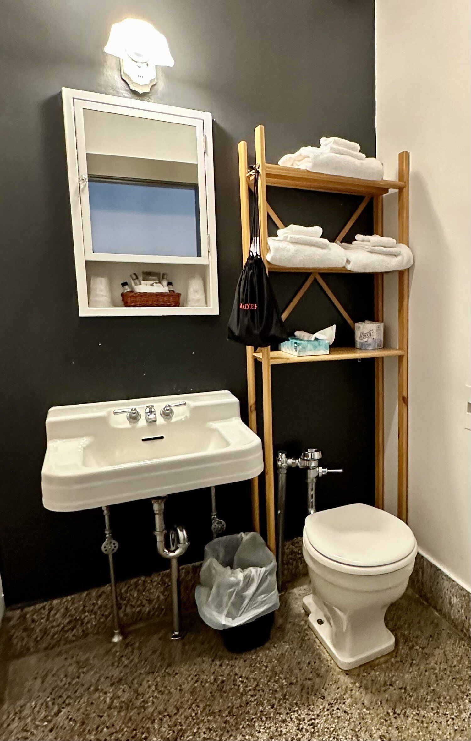 A bathroom with a sink, toilet, and a wooden shelf holding towels.