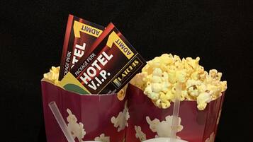 Two popcorn containers with a lid and a straw, placed on a tray filled with popcorn.