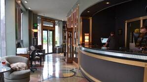 Un hall de hotel con mostrador de recepción, zona de estar y un amplio ventanal.