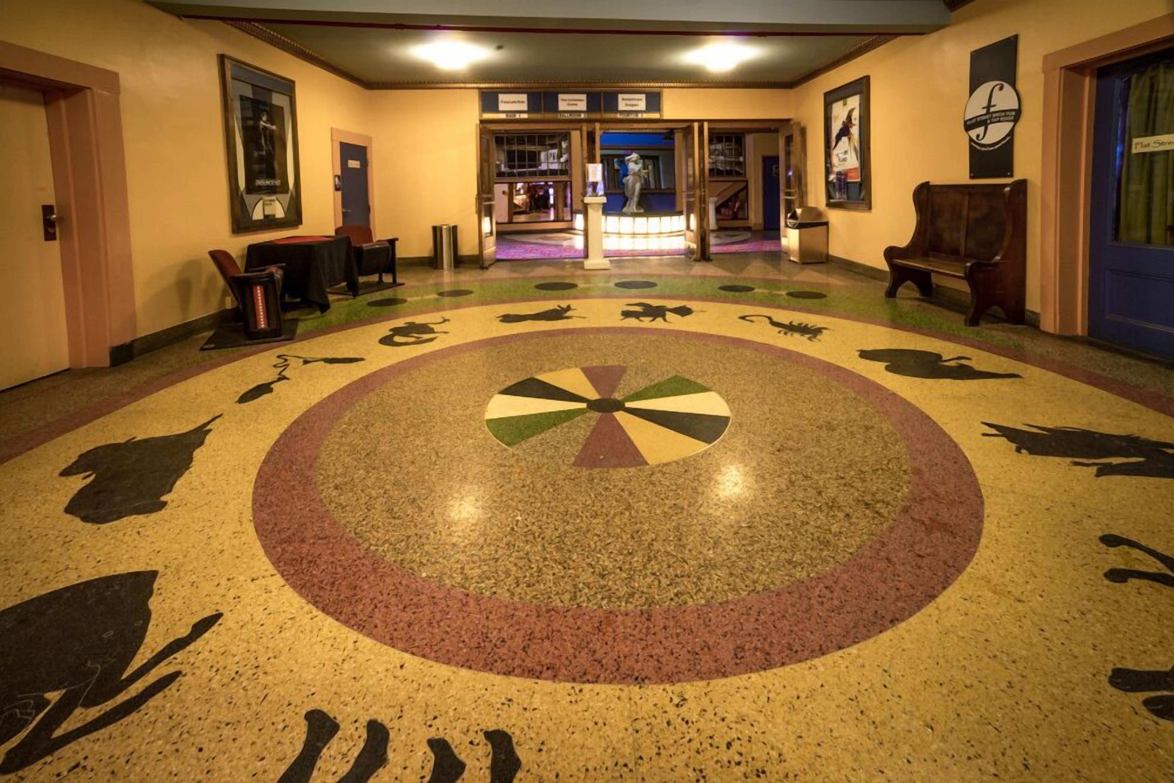 A hotel lobby with a circular floor design, a reception desk, and a statue.