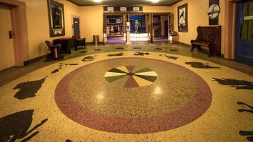 A hotel lobby with a circular floor design, a reception desk, and a statue.