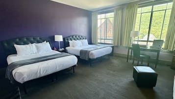 A hotel room with two beds, a desk, and a chair.
