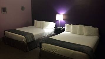 Two twin beds with white linens in a room with purple walls.