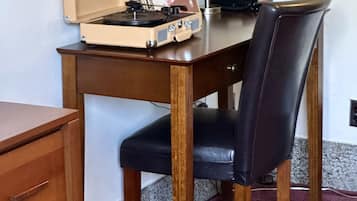 Un escritorio de madera con un tocadiscos antiguo, una lámpara roja y una silla de cuero negro.