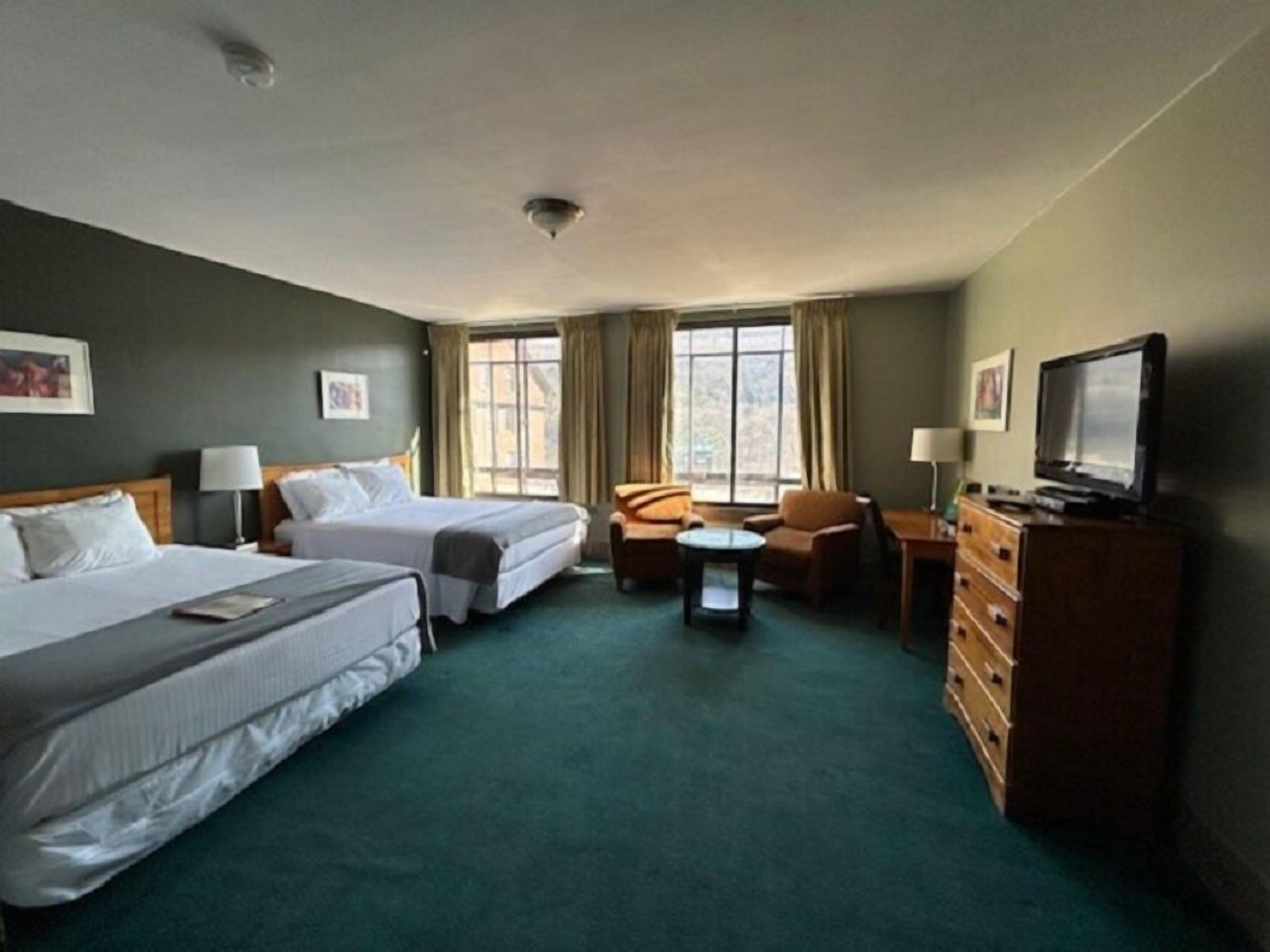 Habitación de hotel con dos camas, un sofá, un televisor y una mesita.