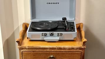 Un tocadiscos Crosley sobre una mesita de madera con un cajón.