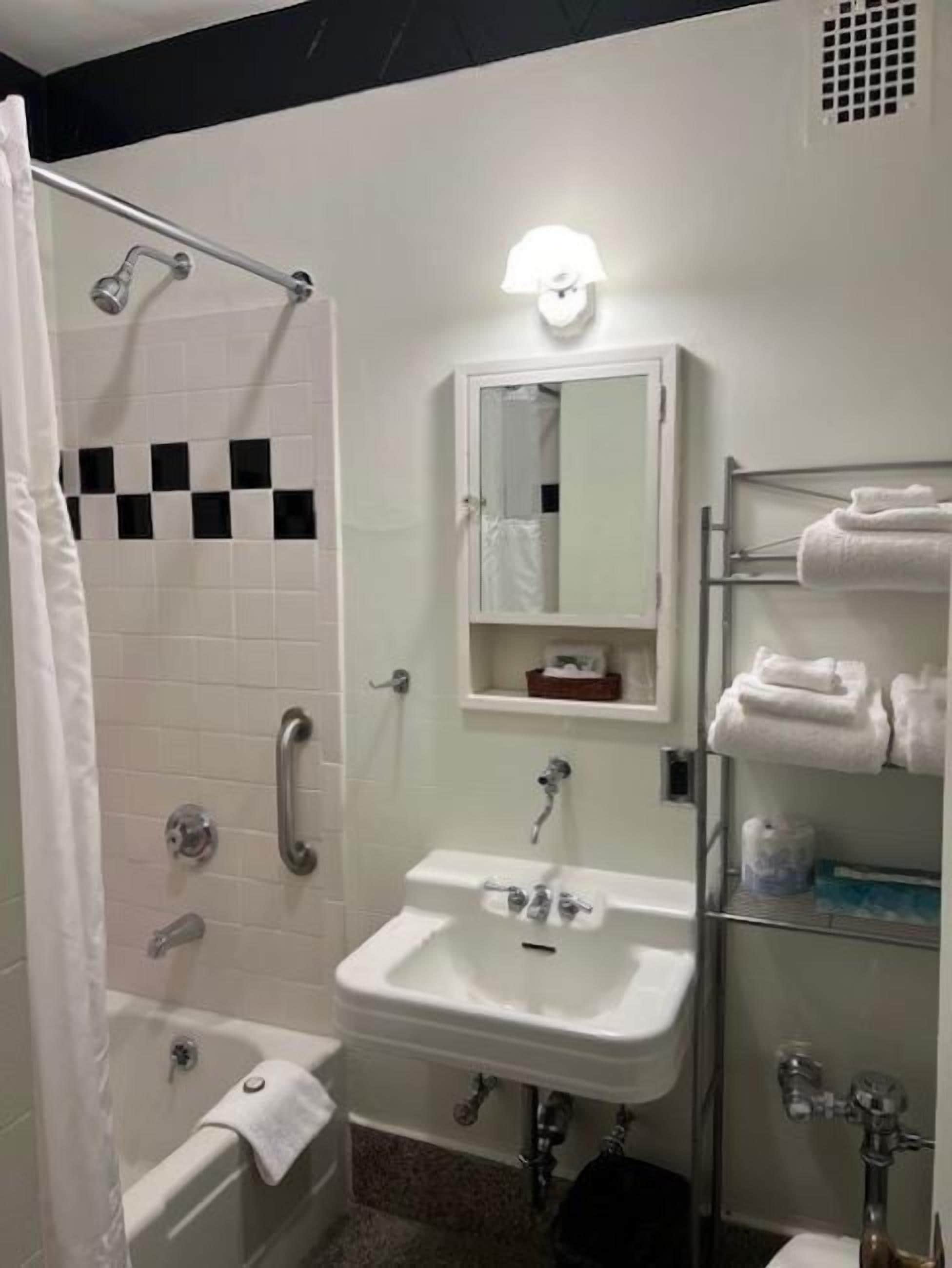 A bathroom with a shower, a sink, a mirror, and a towel rack.
