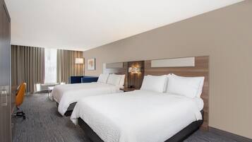 A hotel room with two beds, a desk, and a chair.
