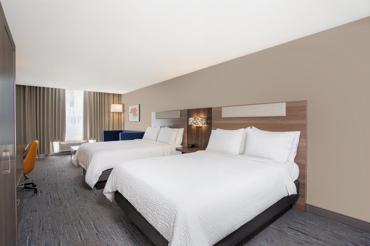 Une chambre d’hôtel avec deux lits, un bureau et une chaise.