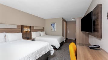 Habitación de hotel con dos camas, un televisor de pantalla plana, un escritorio con control remoto y un cuadro en la pared.
