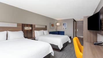 A hotel room with two beds, a desk, a chair, and a TV.