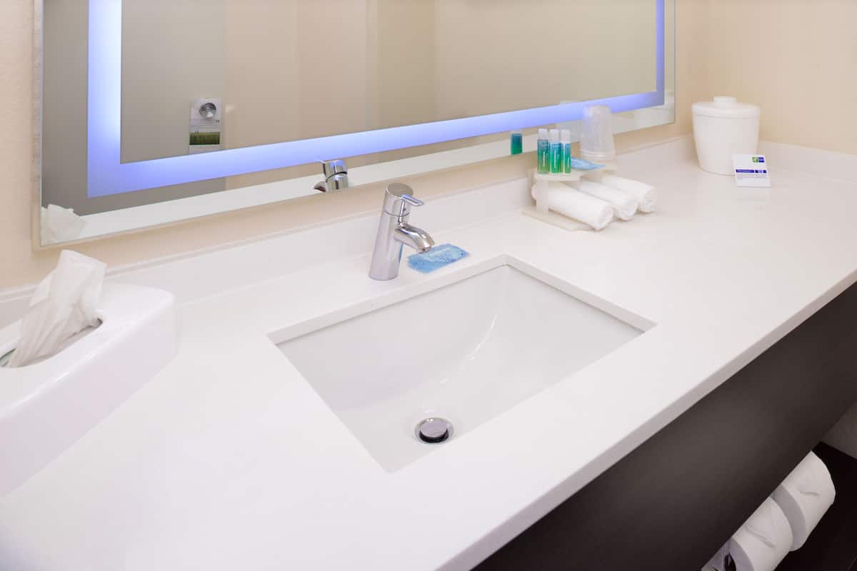 Une salle de bain avec un lavabo blanc, un miroir et des articles de toilette.